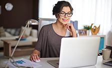 A woman working from home in front of her laptop.